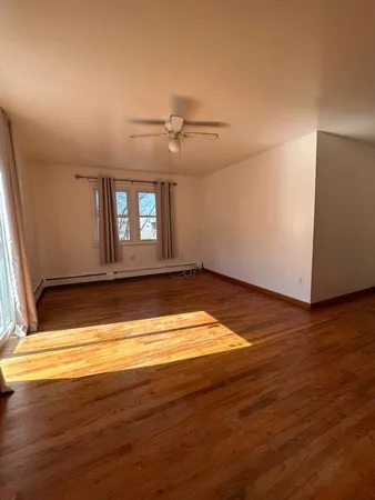 a view of empty room with wooden floor and fan