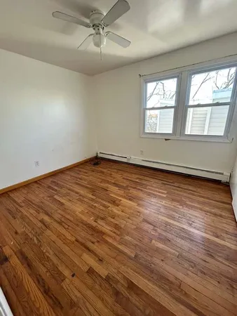 an empty room with wooden floor fan and windows