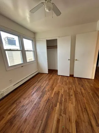 an empty room with wooden floor chandelier fan and windows
