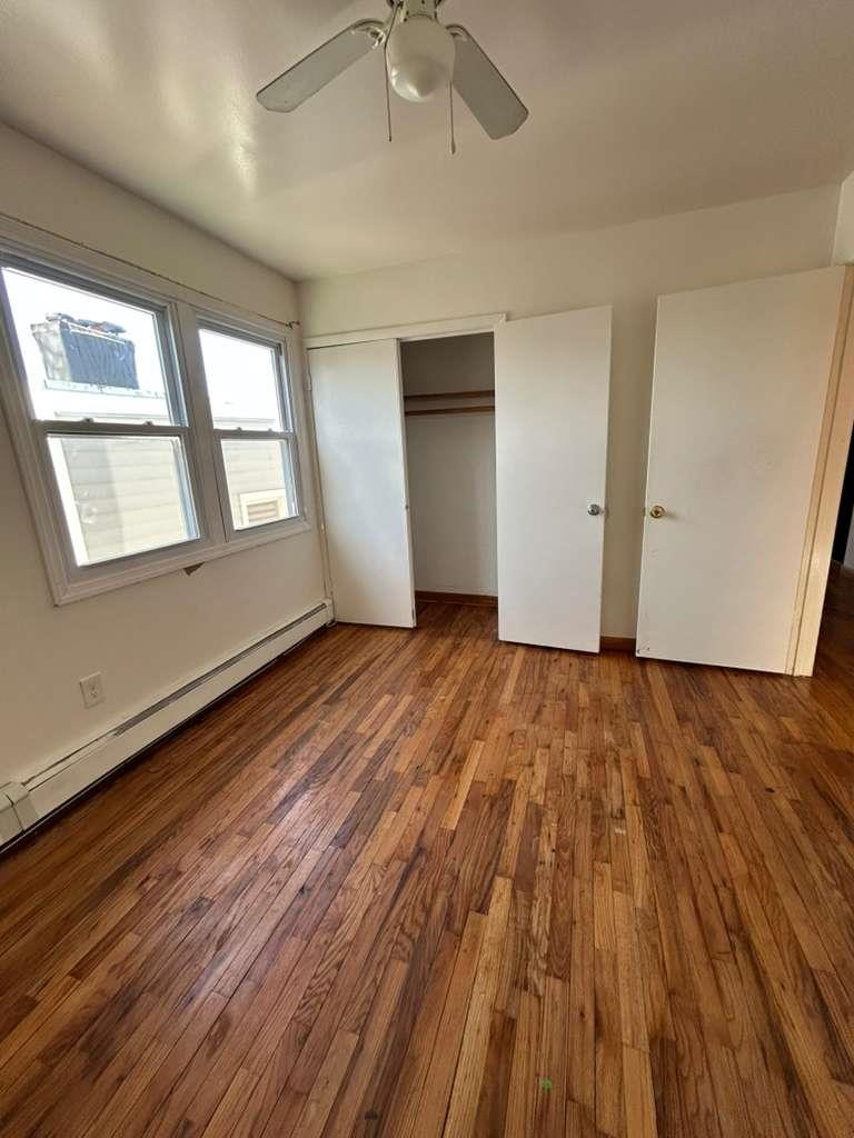 805 Secaucus Road, Unit 2 Jersey City, NJ 07307 - Photo 6 of 21 an empty room with wooden floor chandelier fan and windows
