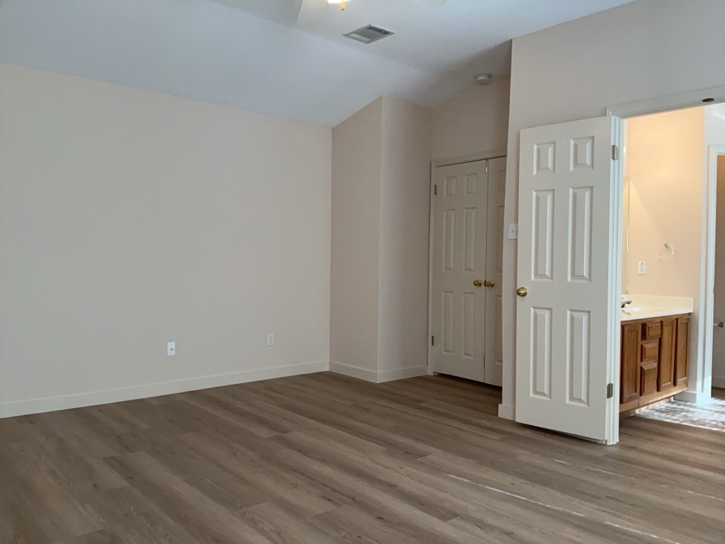1511 Thibodeaux Drive Round Rock, TX 78664 - Photo 18 of 31 Unfurnished bedroom featuring dark wood finished floors, lofted ceiling, a closet, a ceiling fan, and connected bathroom