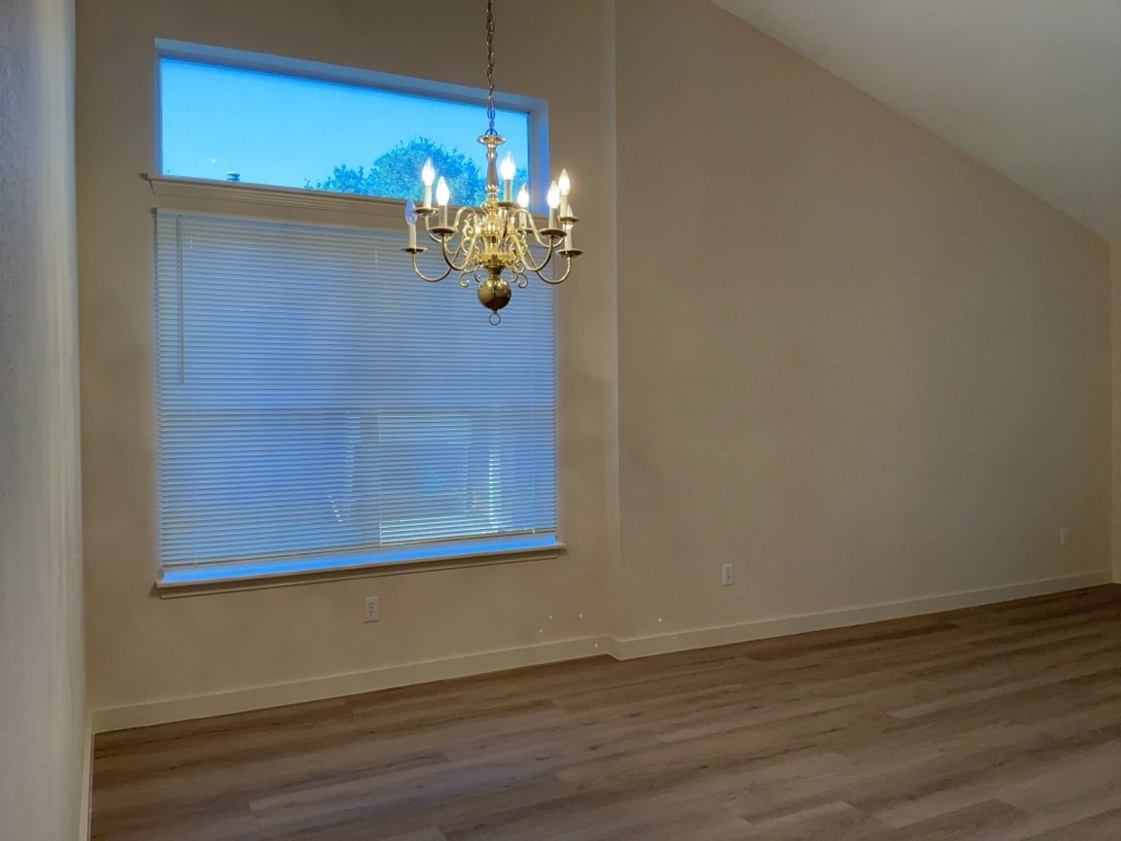 1511 Thibodeaux Drive Round Rock, TX 78664 - Photo 10 of 31 Unfurnished dining area featuring wood finished floors, high vaulted ceiling, and a chandelier