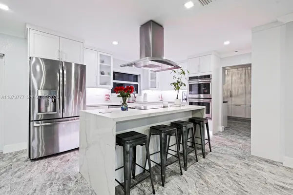 a kitchen with stainless steel appliances kitchen island granite countertop a refrigerator and a stove top oven