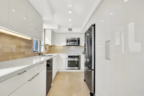 a large kitchen with stainless steel appliances granite countertop a refrigerator and a sink