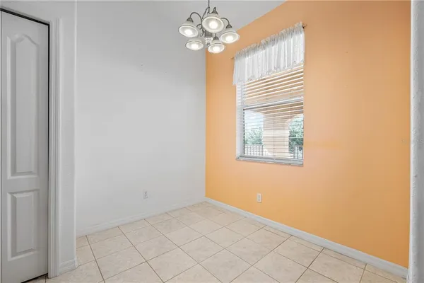 an empty room with chandelier fan and windows