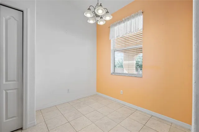 an empty room with chandelier fan and windows