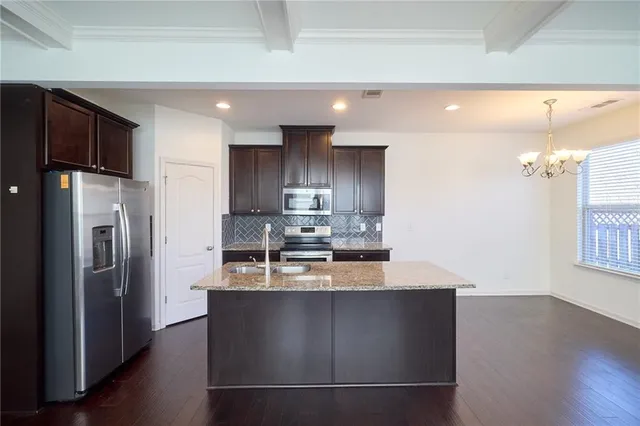 a kitchen with granite countertop stainless steel appliances a sink stove top oven and cabinets