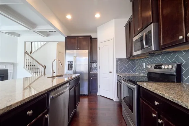 a large kitchen with stainless steel appliances granite countertop wooden cabinets a stove a sink and dishwasher