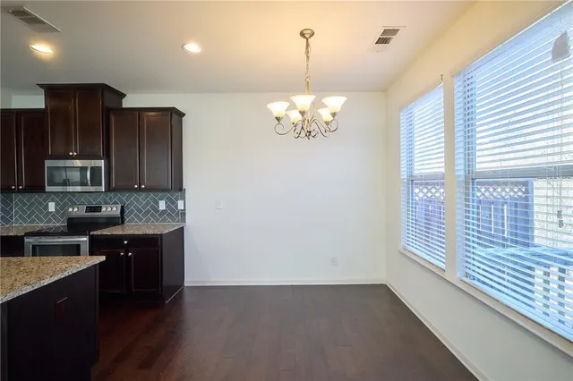 a living room with stainless steel appliances kitchen island granite countertop a sink dishwasher a fireplace with wooden cabinets and wooden floor