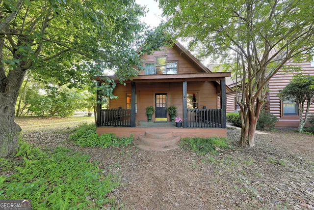 a view of a house with a small yard and a large tree