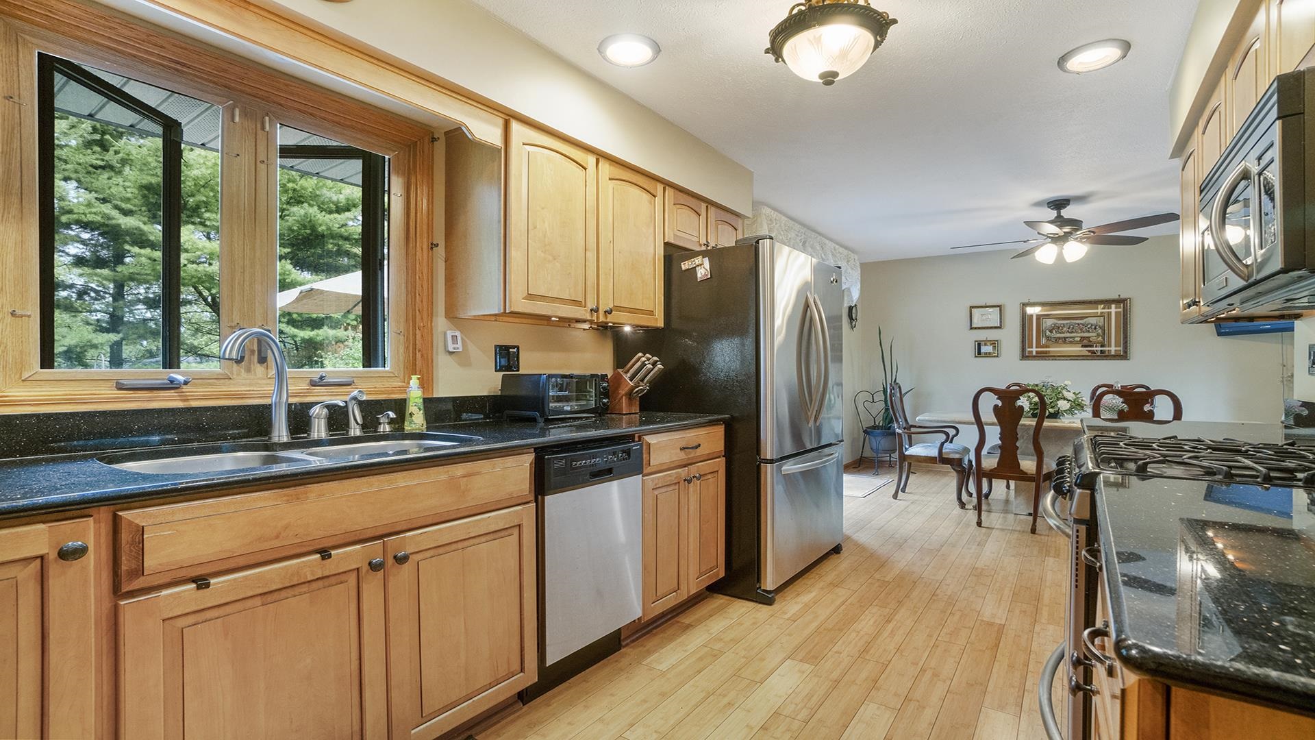 8317 Alan Court Rockford, IL 61108 - Photo 8 of 29 a kitchen with stainless steel appliances granite countertop a stove top oven a sink dishwasher a dining table and chairs with wooden floor
