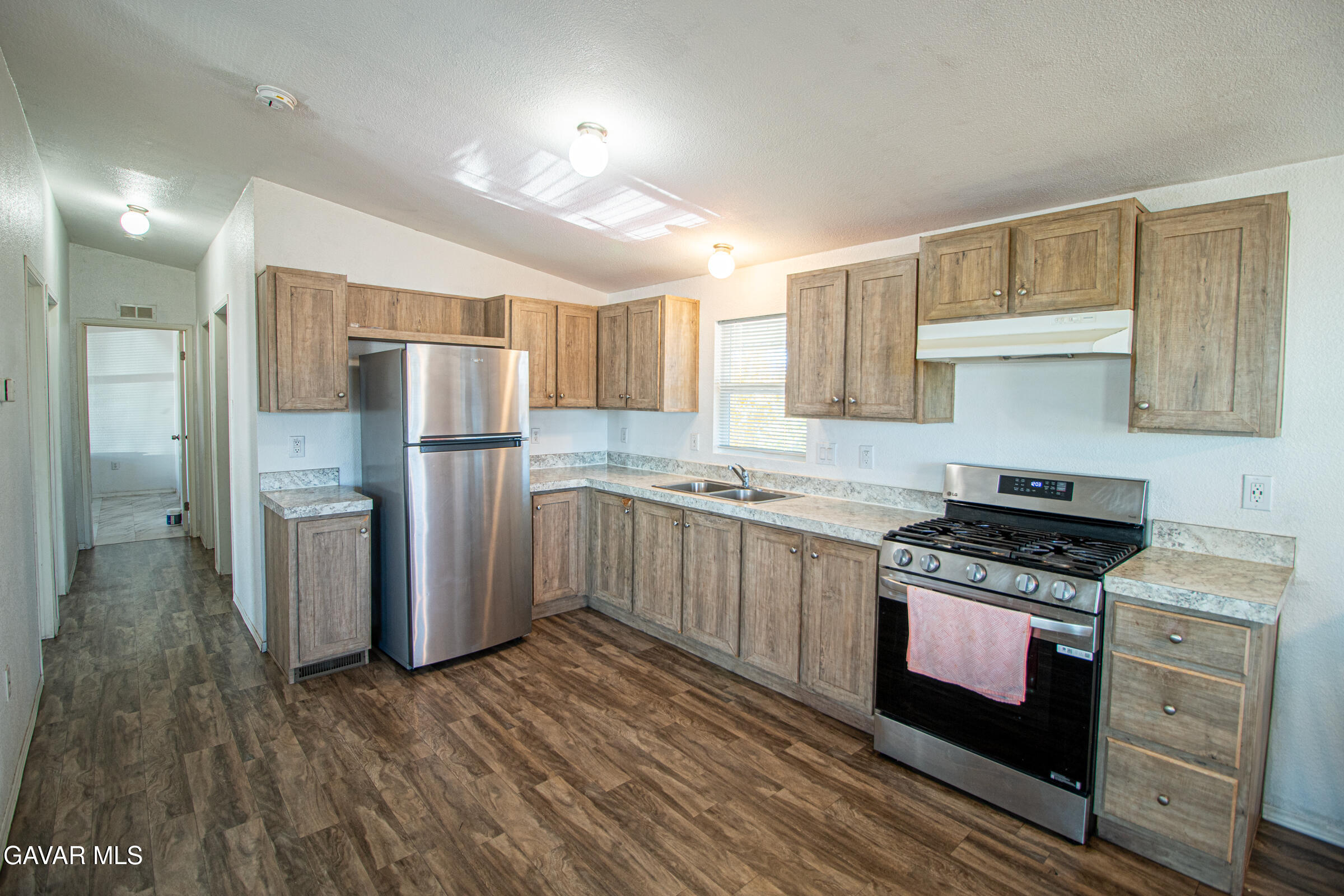 4444 Avenue R Palmdale, CA 93552 - Photo 10 of 17 a kitchen with a refrigerator a sink and wooden cabinets