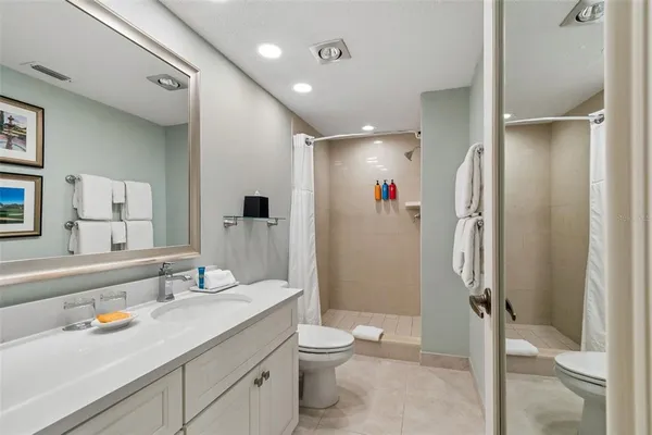 a bedroom with a bed a mirror and a flat tv screen on dresser
