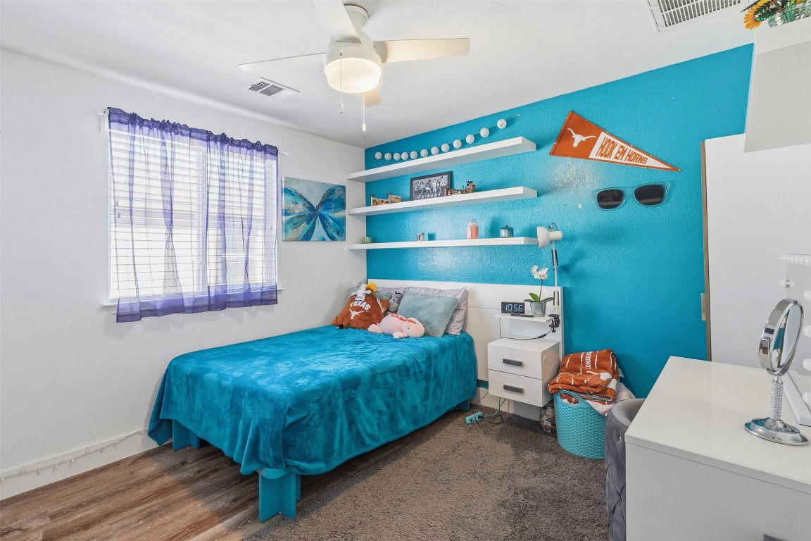 404 Cane River Road Pflugerville, TX 78660 - Photo 16 of 24 a bedroom with a bed and a baby crib with wooden floor