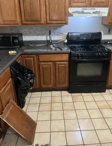 a kitchen with granite countertop a stove a sink and a microwave