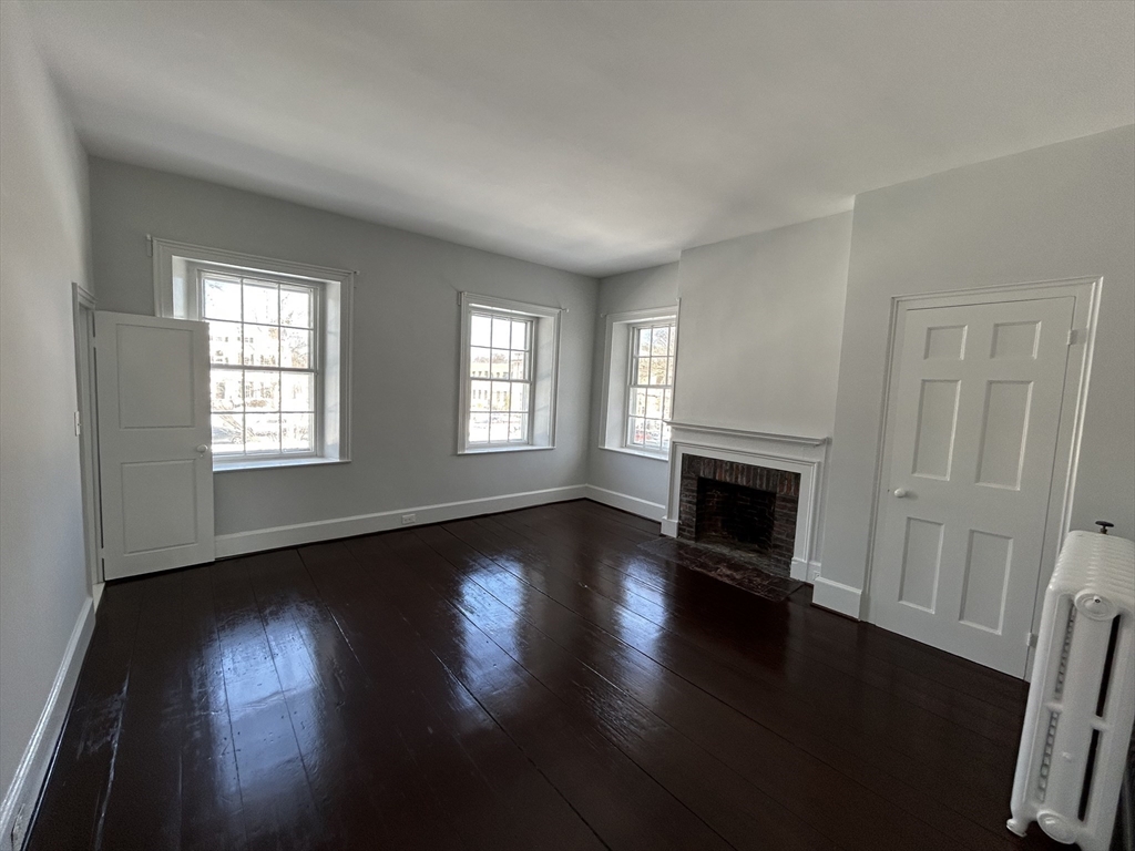 660 High Street Dedham, MA 02026 - Photo 20 of 25 an empty room with wooden floor fireplace and windows