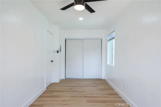an empty room with wooden floor ceiling fan and windows