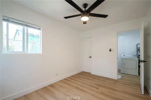 an empty room with wooden floor closet and windows