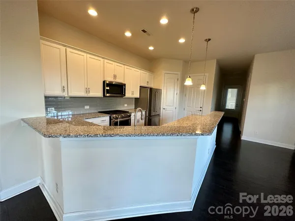 a large kitchen with stainless steel appliances granite countertop a stove a sink a refrigerator a microwave a sink and cabinets