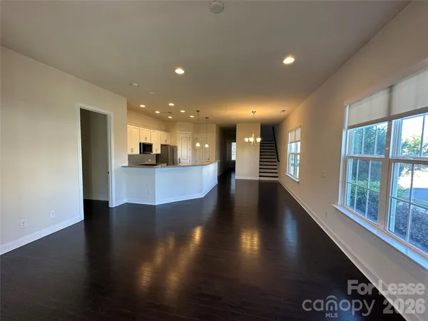 a view of a kitchen with kitchen island a sink wooden floor and a large window