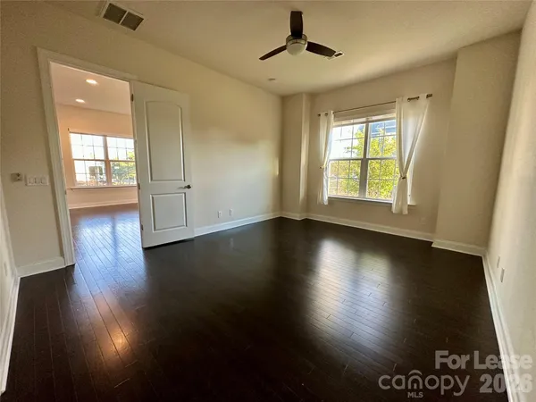 a view of empty room with wooden floor and fan