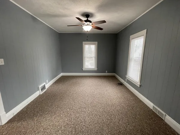 an empty room with a ceiling fan and windows