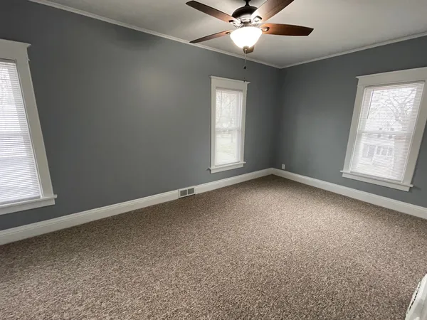 an empty room with a window and a fan