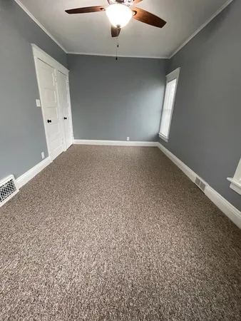 an empty room with a ceiling fan and window