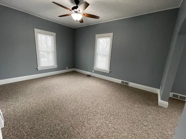 an empty room with windows and fan