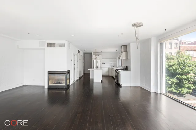 a view of empty room with kitchen view and wooden floor