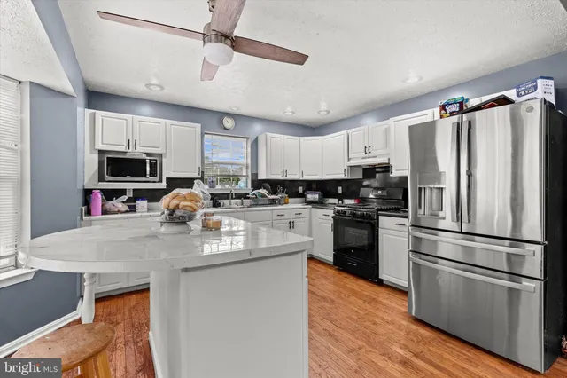 a kitchen with kitchen island a counter top space stainless steel appliances and cabinets
