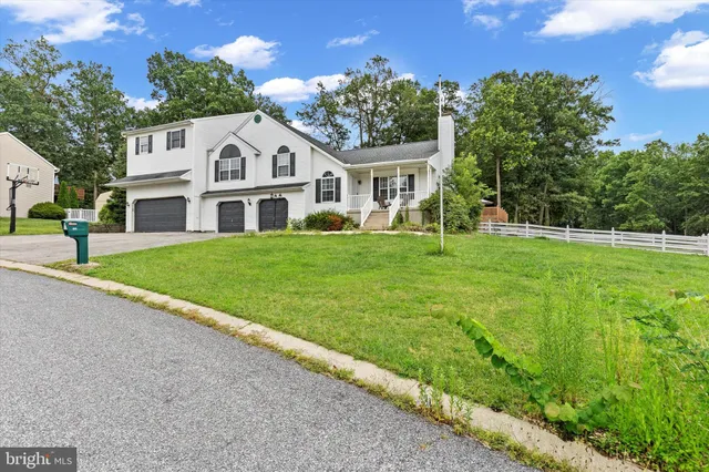 a view of a white house with a big yard and potted plants