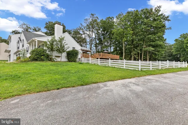 a view of a house with a big yard and large trees