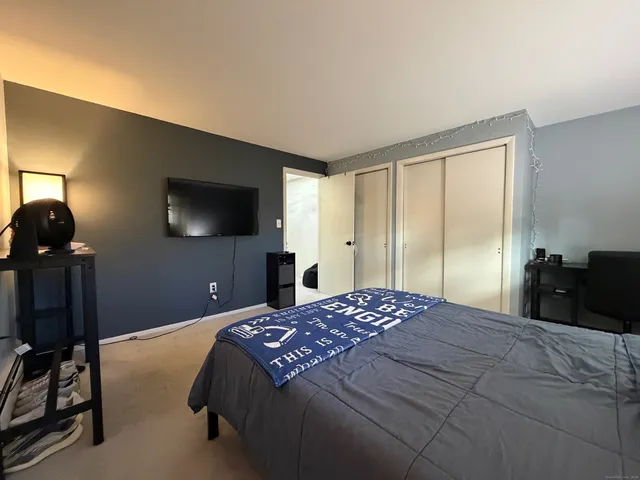 a bedroom with a bed and a flat tv screen on dresser