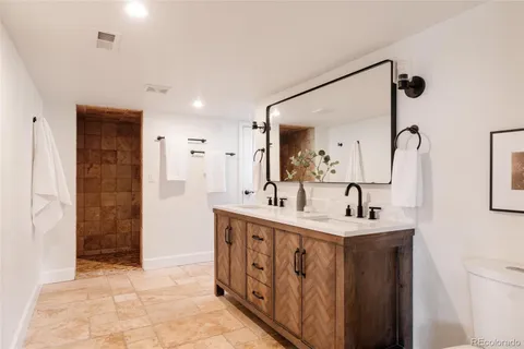 a spacious bathroom with a double vanity sink a mirror and shower