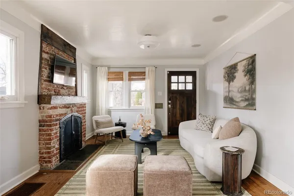 a living room with furniture two windows and a fireplace