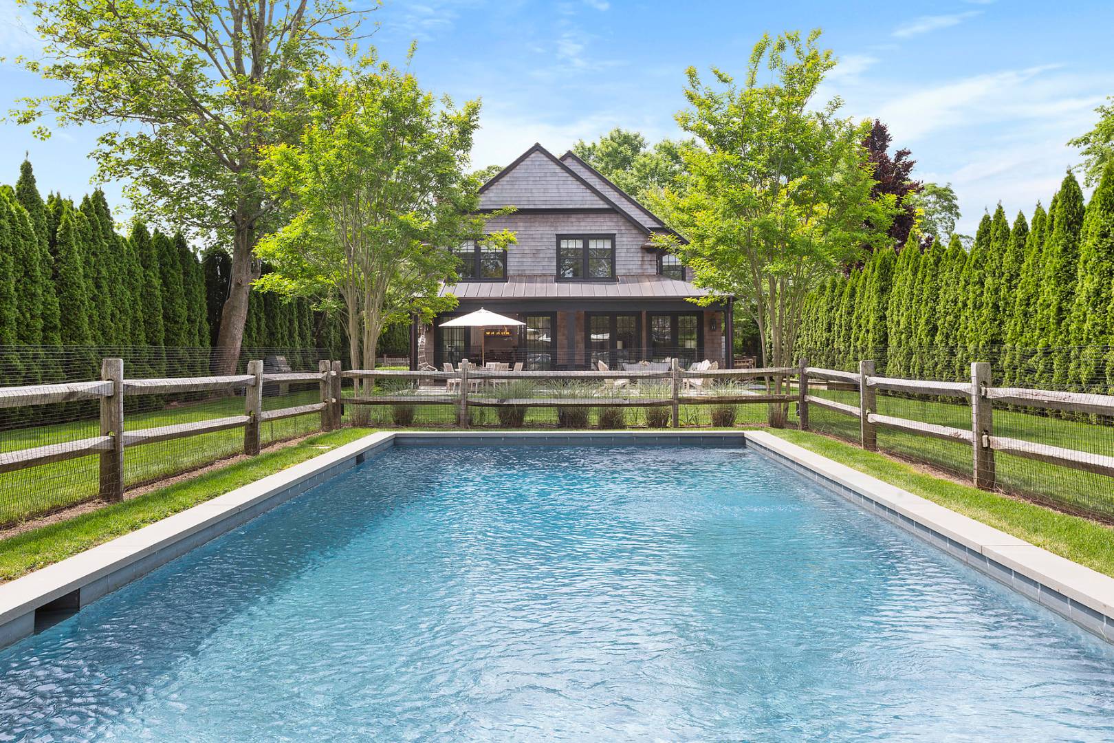 a view of house with swimming pool and a yard