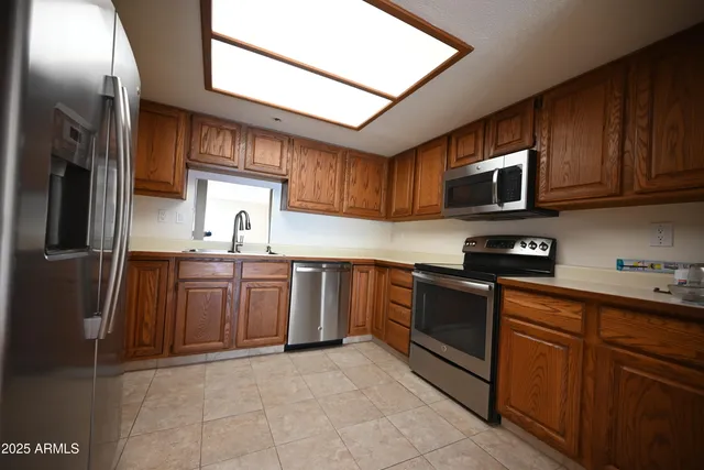 a kitchen with stainless steel appliances granite countertop a refrigerator a stove top oven a sink and dishwasher