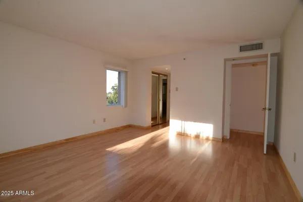 a view of an empty room with wooden floor and a window