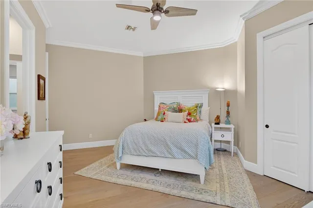 a bedroom with a bed a dresser and potted plants
