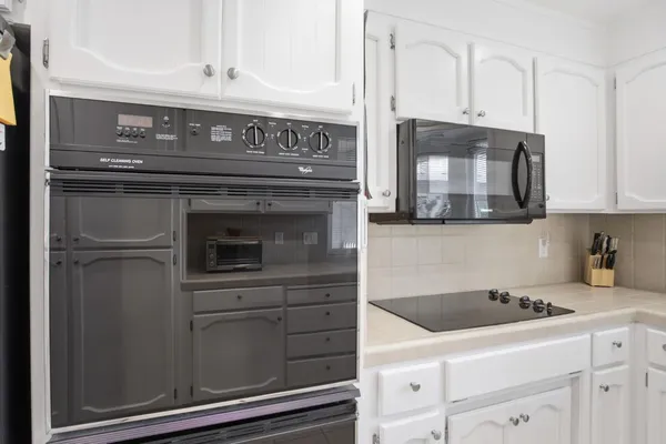 a large white kitchen with a sink and dishwasher a stove top oven with wooden floor