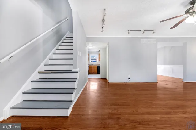 a view of empty room with wooden floor and fan