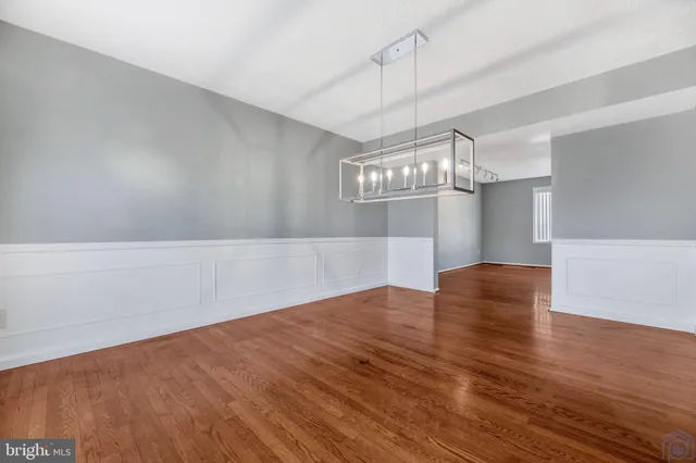 an empty room with wooden floor ceiling fan and window