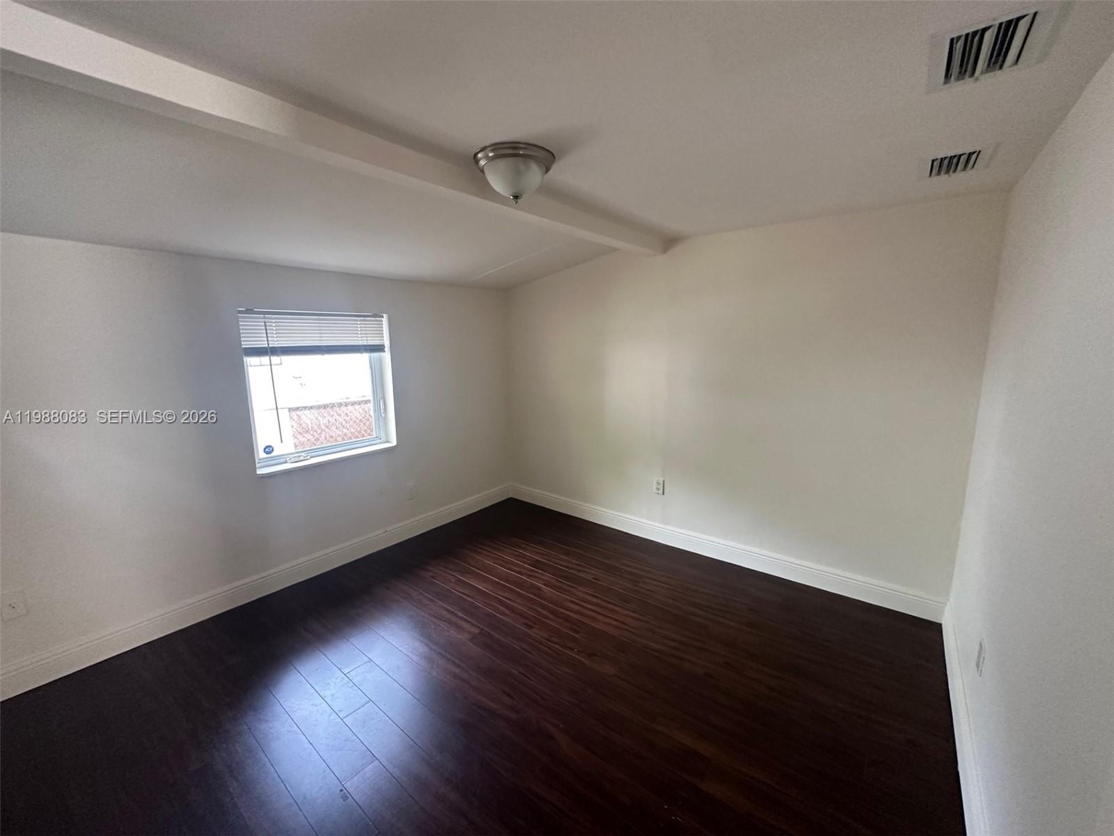 565 Northeast 65th Street, Unit 2 Miami, FL 33138 - Photo 6 of 7 a view of an empty room with wooden floor and a window