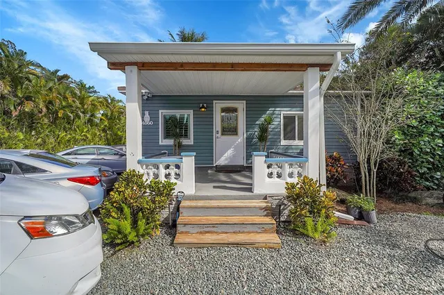 a view of a house with potted plants and a large tree