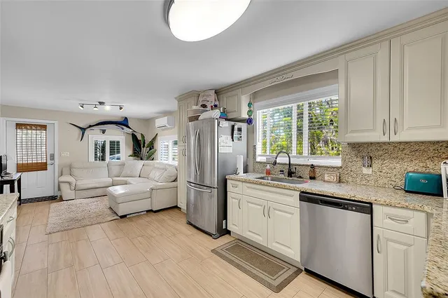 a kitchen with a sink dishwasher a dining table and chairs with wooden floor