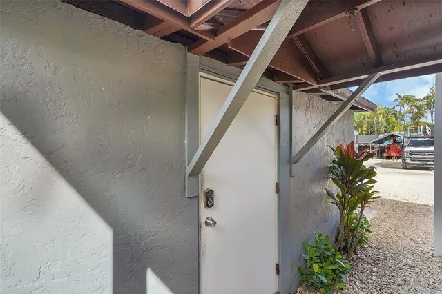 a view of a white house with large trees plants and a large tree
