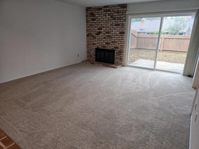 a view of an empty room with fireplace and a window