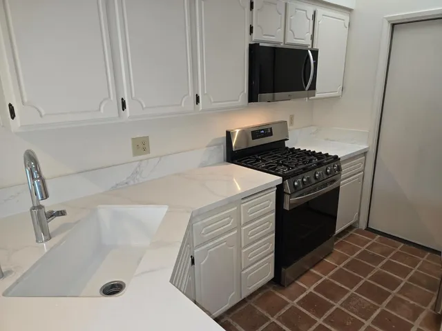 a kitchen with granite countertop a sink and a stove top oven
