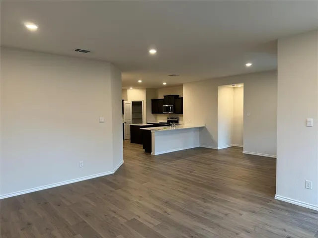 a large kitchen with stainless steel appliances a large counter top a stove and a refrigerator